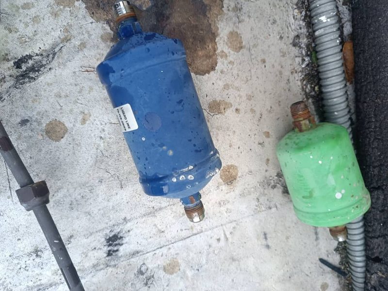 Dos filtros secadores en el suelo: uno verde, usado, y otro azul, nuevo.