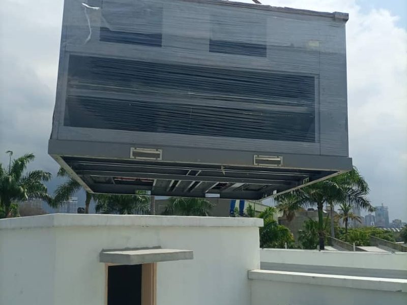 Un equipo de aire acondicionado central suspendido de una grúa sobre la azotea de un edificio de Caracas.