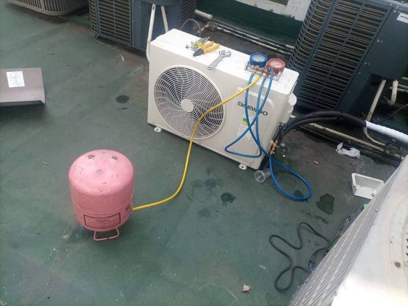 Condensadora en una azotea conectada a un juego de manómetros y a una bombona de refrigerante.
